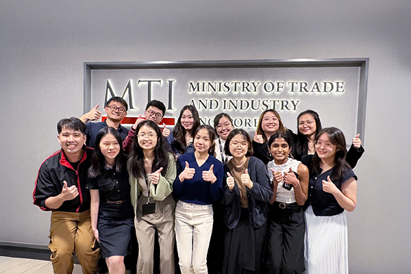 Group of MTI interns smiling and giving thumbs up at the MTI sign.